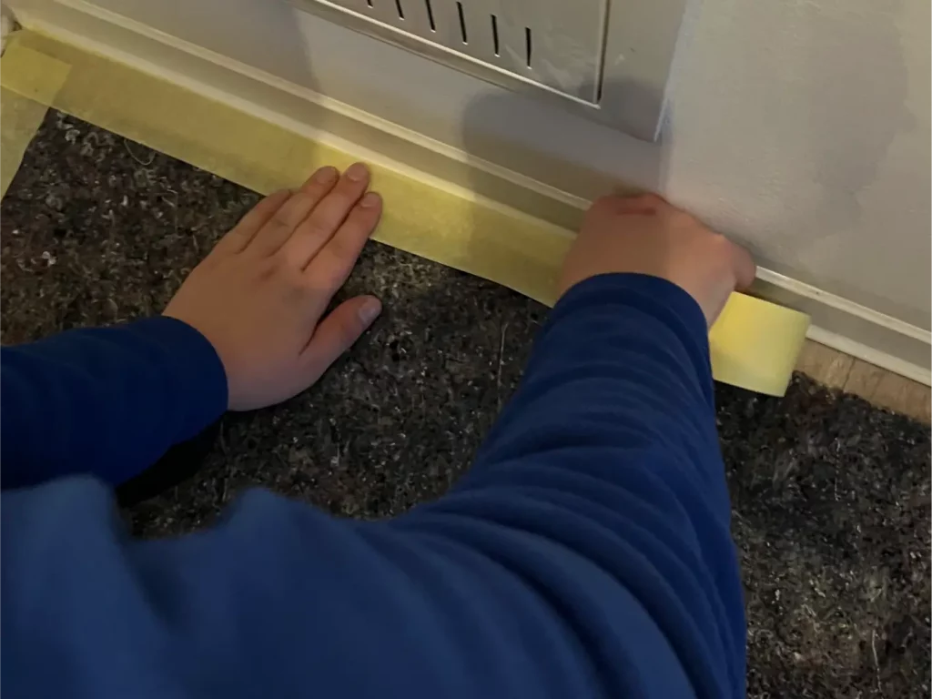 Person klebt Abdeckband auf Boden